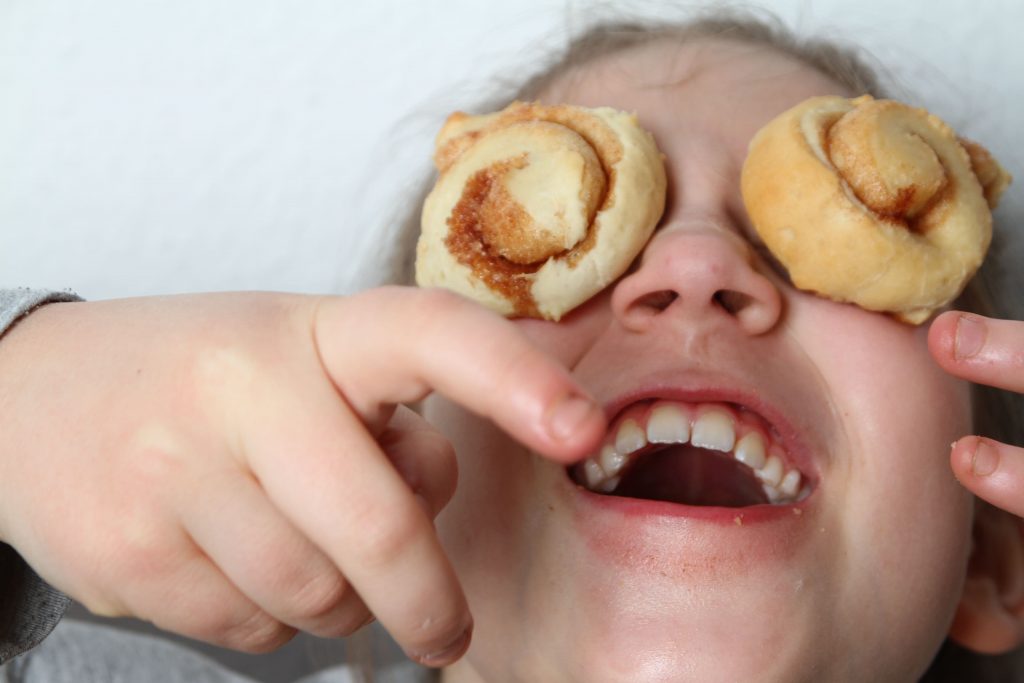 imagen de una niña riendonse con dos galletas puestas en los ojos