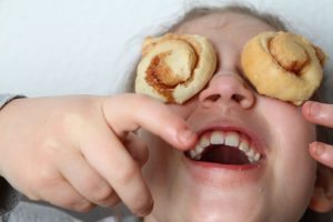 imagen de una niña riendonse con dos galletas puestas en los ojos
